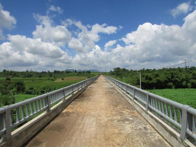 The bridge spans a lush green valley near Da Bang Lake